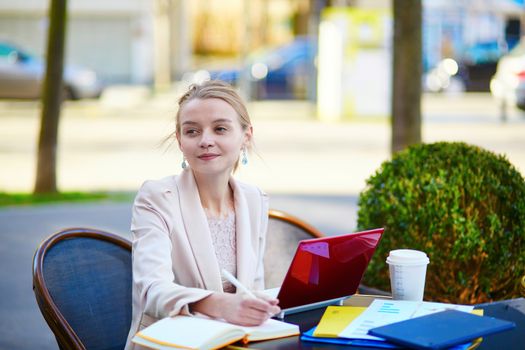 Young businesswoman on a coffee break, working on her laptop