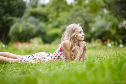 Beautiful young girl lying on the grass on a summer day 