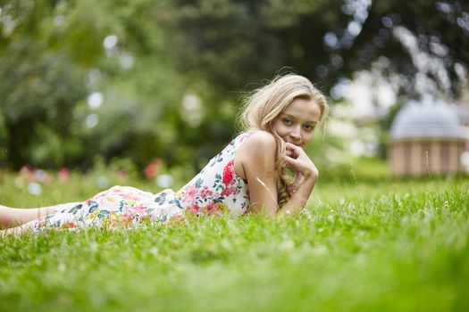 Beautiful young girl lying on the grass on a summer day 
