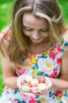 Girl holding colorful French macaroons in hands