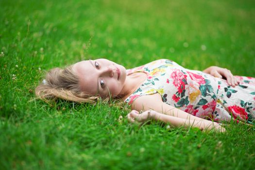 Beautiful young girl lying on the grass on a summer day