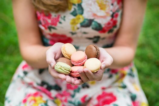 Closeup of female hands holding colorful French macaroons
