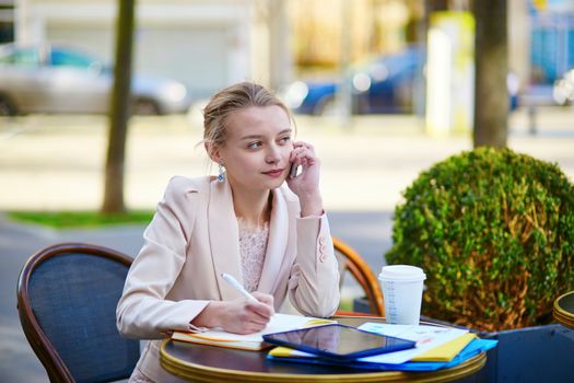 Young businesswoman on a coffee break, working and speaking on the phone