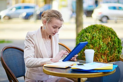 Young businesswoman on a coffee break, working and using her tablet