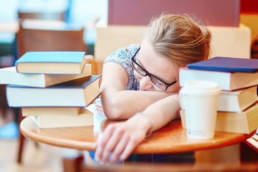 Exhausted student with books and papers, studying at home. Quarantine and closed schools and offices during coronavirus outbreak. Homeschooling, distance learning and freelance job
