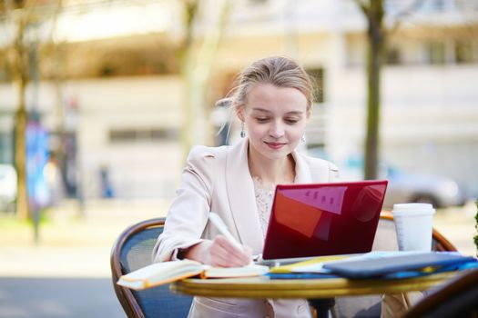 Young businesswoman on a coffee break, using her mobile laptop