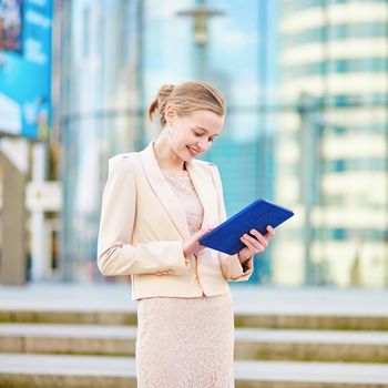 Young beautiful business woman in modern glass interior using tablet