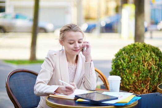Young businesswoman on a coffee break, using her mobile phone