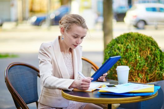 Young businesswoman on a coffee break, working and using her tablet
