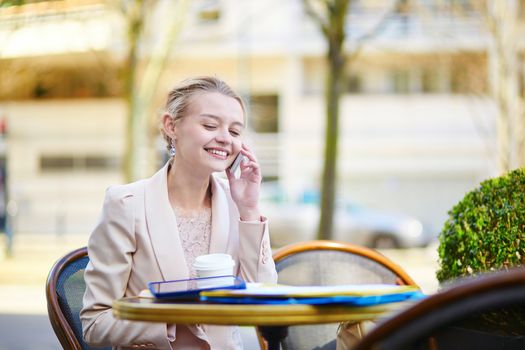 Young businesswoman on a coffee break, working and speaking on the phone