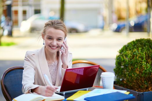 Young businesswoman on a coffee break, using her mobile phone