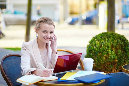 Young businesswoman on a coffee break, using her mobile phone