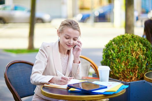 Young businesswoman on a coffee break, working and speaking on the phone