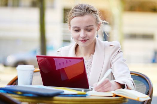 Young businesswoman on a coffee break, using her mobile laptop. Quarantine and closed offices during coronavirus outbreak