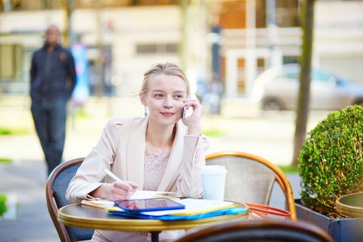 Young businesswoman on a coffee break, working and speaking on the phone