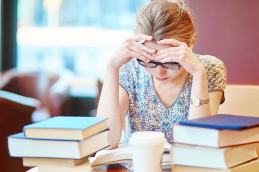 Exhausted student with books and papers, studying at home. Quarantine and closed schools and offices during coronavirus outbreak. Homeschooling, distance learning and freelance job