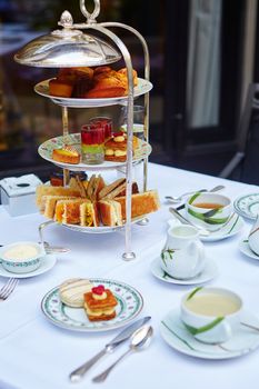 Beautiful table setting with selection of sandwiches, fancy cakes, tea and champagne served for the ceremony of afternoon tea