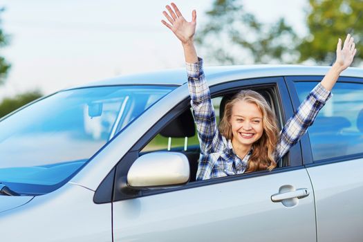 Happy young woman looking out of the car window