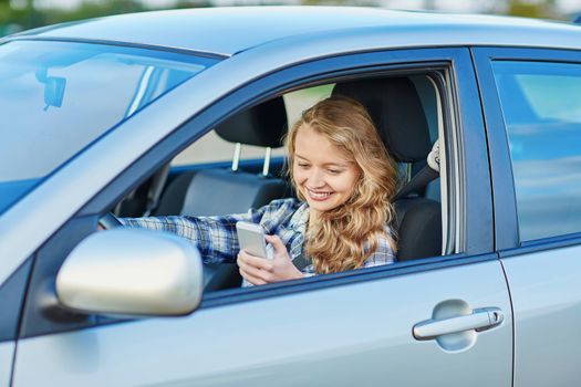 Young woman using her smartphone while driving a car