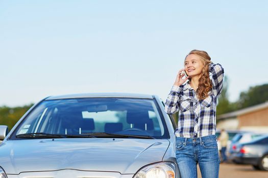 Young woman on the road near a broken car calling for help