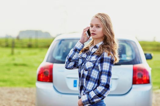 Young woman on the road near a broken car calling for help