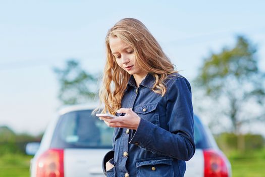 Young woman on the road near a broken car calling for help