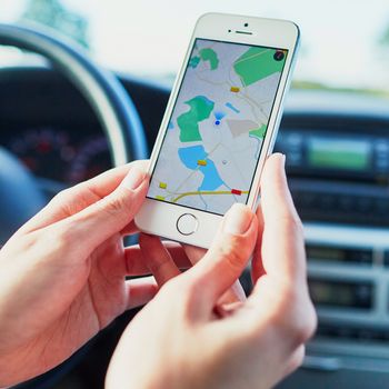 Female driver hands holding a phone with interface navigator on a screen