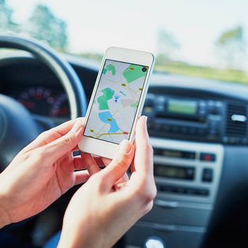 Female driver hands holding a phone with interface navigator on a screen