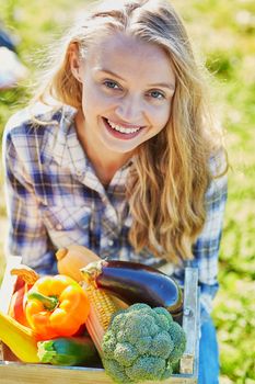 Woman holding wooden crate with fresh organic vegetables from farm
