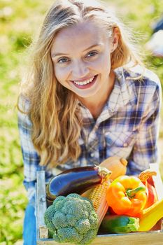 Woman holding wooden crate with fresh organic vegetables from farm