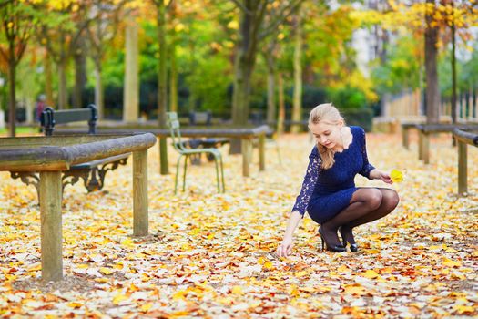 Beautiful young woman in blue dress in the Luxembourg garden of Paris on a fall day