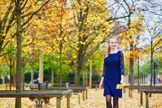 Beautiful young woman in blue dress in the Luxembourg garden of Paris on a fall day