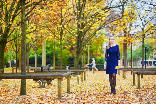 Beautiful young woman in blue dress in the Luxembourg garden of Paris on a fall day