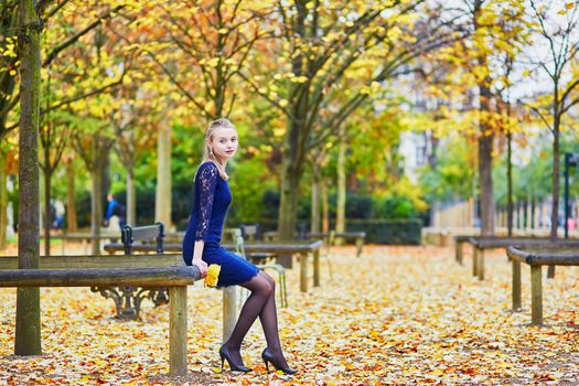 Beautiful young woman in blue dress in the Luxembourg garden of Paris on a fall day