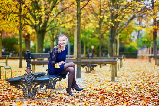 Beautiful young woman in blue dress in the Luxembourg garden of Paris on a fall day
