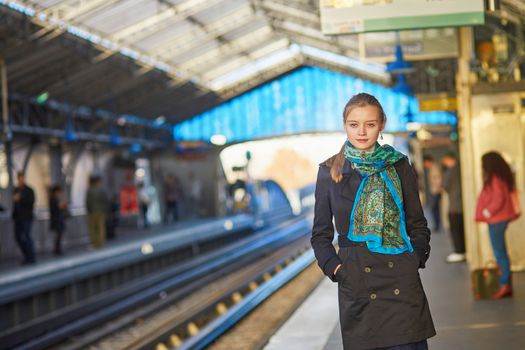 Beautiful young woman waiting for a train on the platform of Parisian underground