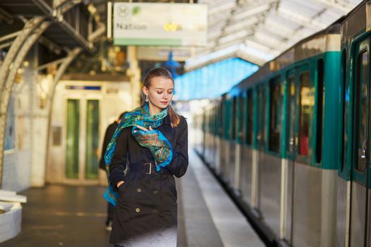 Beautiful young woman waiting for a train on the platform of Parisian underground