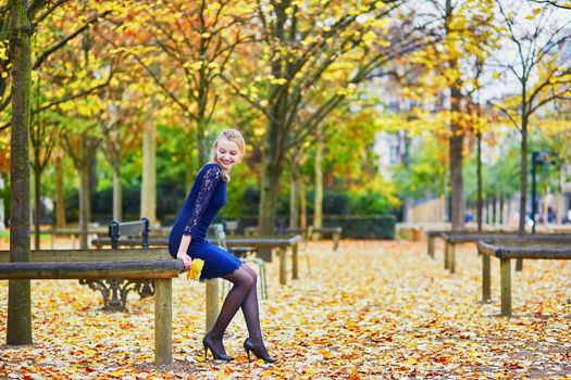 Beautiful young woman in blue dress in the Luxembourg garden of Paris on a fall day