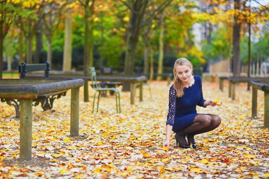 Beautiful young woman in blue dress in the Luxembourg garden of Paris on a fall day