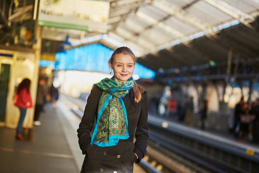 Beautiful young woman waiting for a train on the platform of Parisian underground