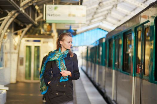 Beautiful young woman waiting for a train on the platform of Parisian underground