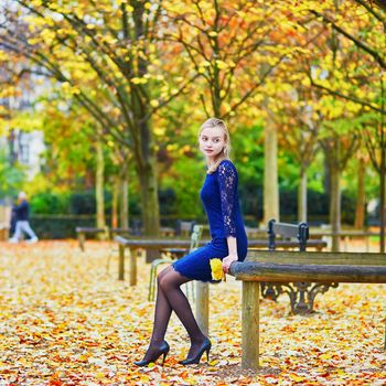 Beautiful young woman in blue dress in the Luxembourg garden of Paris on a fall day