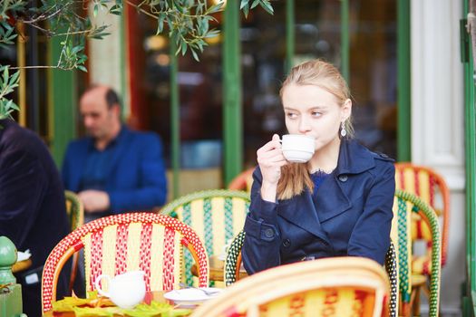 Young woman drinking hot chocolate in Parisian outdoor cafe