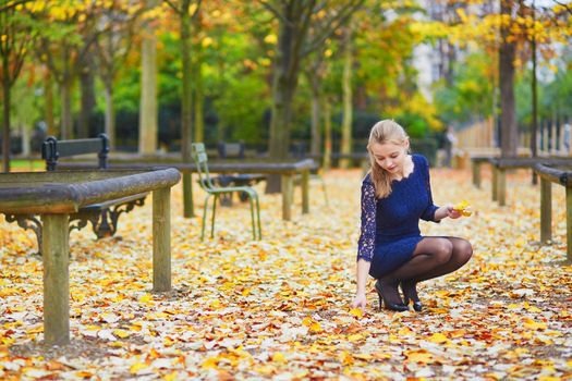 Beautiful young woman in blue dress in the Luxembourg garden of Paris on a fall day