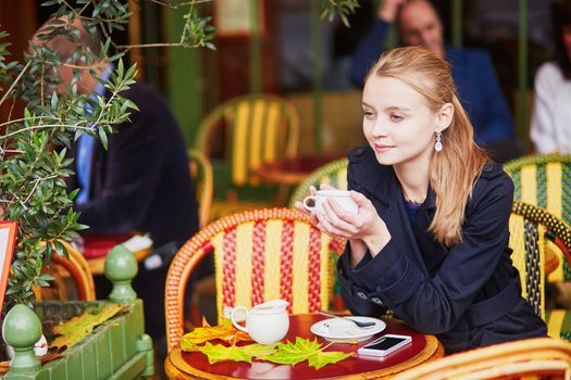 Young woman drinking hot chocolate in Parisian outdoor cafe