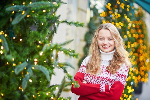 Girl with a brightly decorated Christmas tree in Paris
