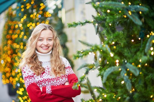 Girl with a brightly decorated Christmas tree in Paris