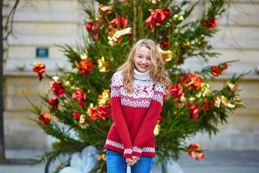Girl with a brightly decorated Christmas tree in Paris