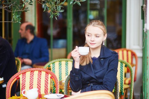 Young woman drinking hot chocolate in Parisian outdoor cafe