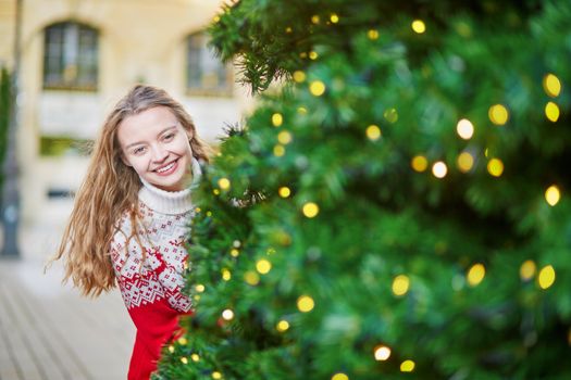 Cheerful young woman on a street of Paris decorated for Christmas